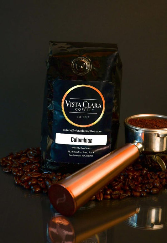 Vista Clara Coffee bag labeled Colombian with a portafilter and coffee beans on a reflective surface